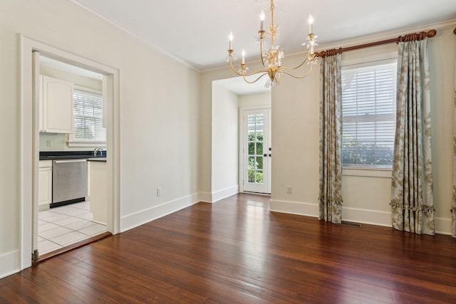 empty room featuring ornamental molding, plenty of natural light, wood-type flooring, and a chandelier