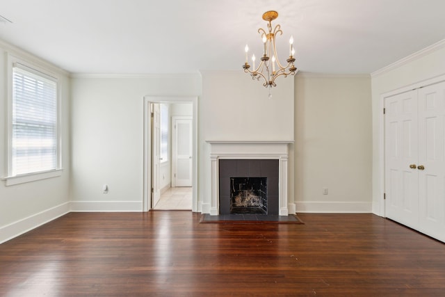 unfurnished living room with dark wood-type flooring, a tile fireplace, a chandelier, and ornamental molding