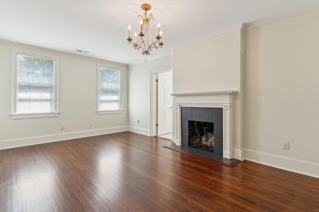 unfurnished living room with ornamental molding, dark hardwood / wood-style floors, a tile fireplace, and a chandelier