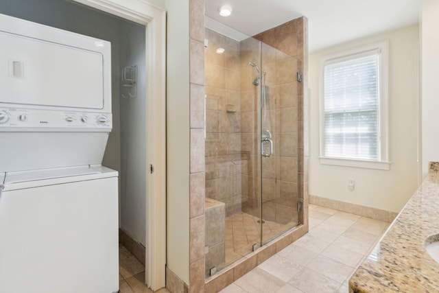 bathroom with a shower with door, stacked washer and clothes dryer, vanity, and tile patterned floors