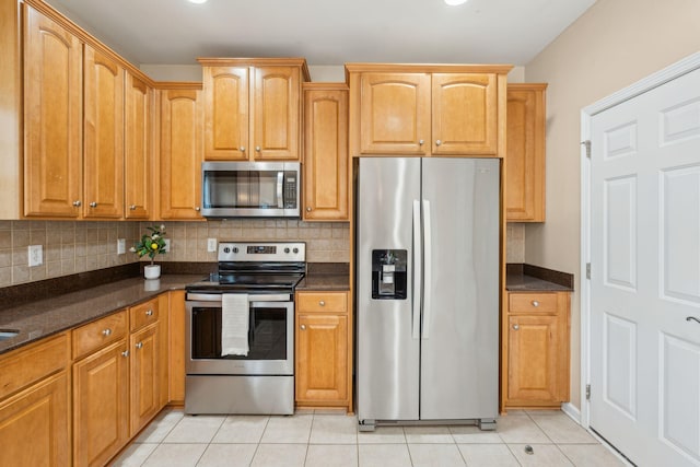 489 Dolphin Dr, Summerville, SC 29485 - kitchen featuring stainless steel appliances, light tile patterned floors, backsplash, dark stone countertops, and brown cabinetry