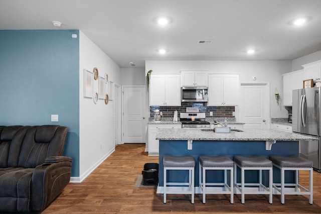 671 Silver Spruce St, Summerville, SC 29486 - kitchen featuring stainless steel appliances, open floor plan, a kitchen bar, white cabinetry, and decorative backsplash