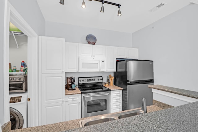 kitchen featuring appliances with stainless steel finishes, rail lighting, light stone counters, white cabinets, and washer / dryer