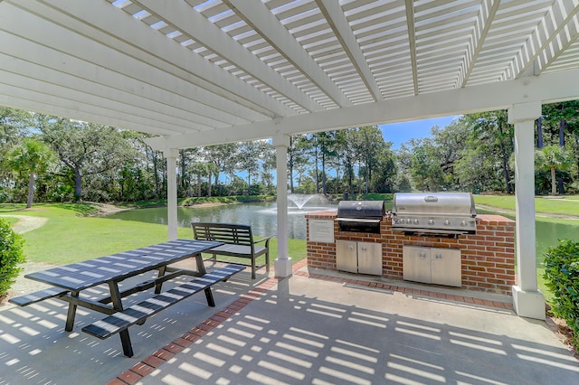 view of patio with an outdoor kitchen, a water view, grilling area, and a pergola