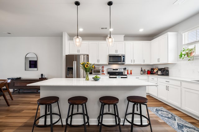 582 Mclernon Trce, Johns Island, SC 29455 - kitchen featuring appliances with stainless steel finishes, a kitchen island, a kitchen bar, backsplash, and white cabinetry