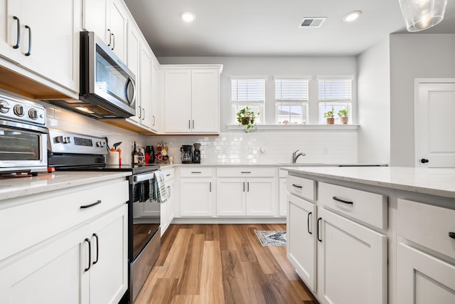 582 Mclernon Trce, Johns Island, SC 29455 - kitchen featuring appliances with stainless steel finishes, light wood-style floors, white cabinetry, decorative backsplash, and recessed lighting