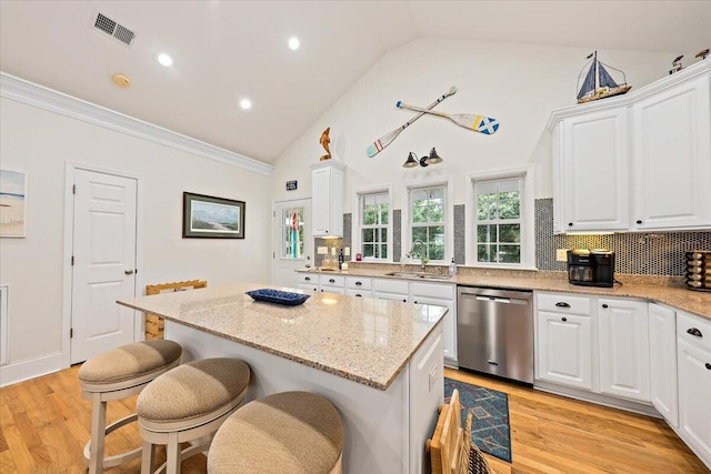 1604 Jungle Rd, Edisto Island, SC 29438 - kitchen with dishwasher, white cabinetry, a kitchen island, a kitchen bar, and decorative backsplash