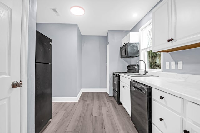 kitchen featuring sink, light hardwood / wood-style floors, white cabinets, and black appliances