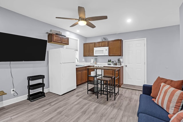 kitchen featuring white appliances, light wood-type flooring, ceiling fan, and sink