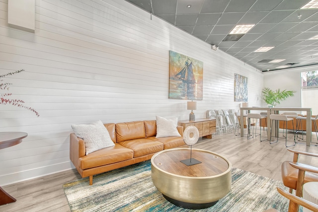 living room featuring a drop ceiling, hardwood / wood-style flooring, and wood walls