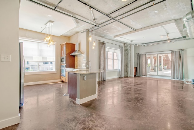 kitchen with wall chimney exhaust hood, a breakfast bar area, appliances with stainless steel finishes, pendant lighting, and light stone countertops