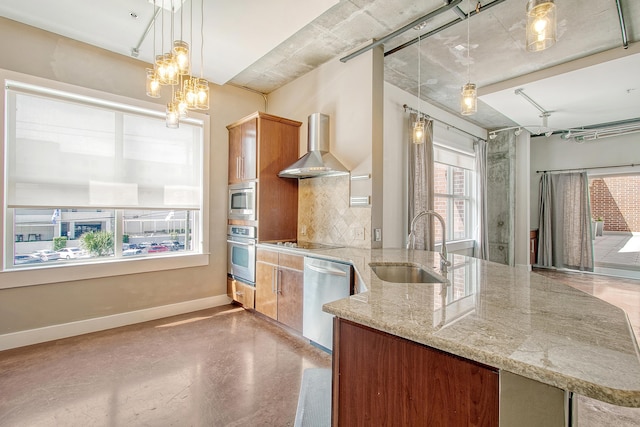 kitchen with sink, light stone counters, pendant lighting, stainless steel appliances, and wall chimney range hood