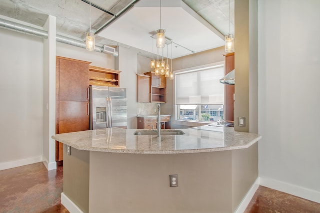 kitchen featuring stainless steel refrigerator with ice dispenser, sink, hanging light fixtures, kitchen peninsula, and light stone countertops