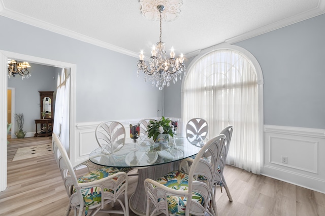 dining room featuring ornamental molding, a textured ceiling, light hardwood / wood-style flooring, and a notable chandelier