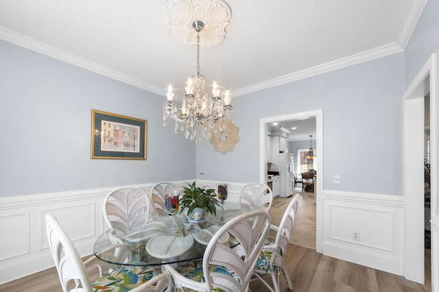 dining room with hardwood / wood-style flooring, ornamental molding, and a chandelier