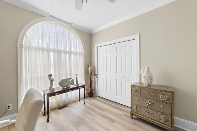 living area with ornamental molding, ceiling fan, a textured ceiling, and light hardwood / wood-style floors