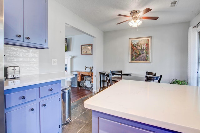 kitchen with dark tile flooring, tasteful backsplash, ceiling fan, and a textured ceiling