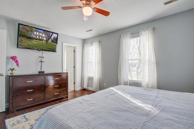 bedroom featuring a textured ceiling, multiple windows, ceiling fan, and dark wood-type flooring