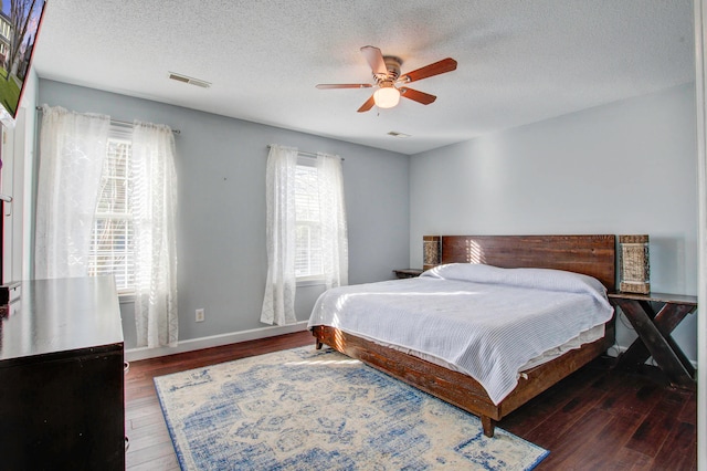 bedroom featuring dark hardwood / wood-style flooring, ceiling fan, a textured ceiling, and multiple windows