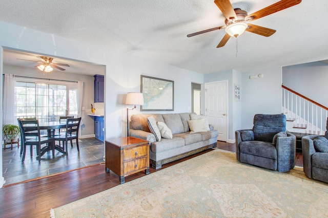 living room featuring ceiling fan, dark hardwood / wood-style floors, and a textured ceiling