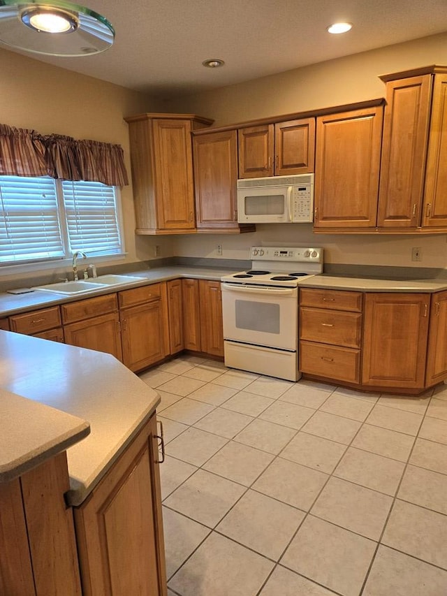 kitchen featuring light tile patterned flooring, kitchen peninsula, sink, and white appliances