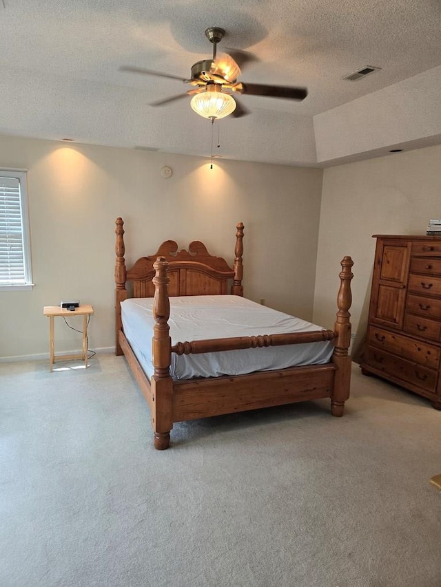 bedroom with a textured ceiling, ceiling fan, and light colored carpet