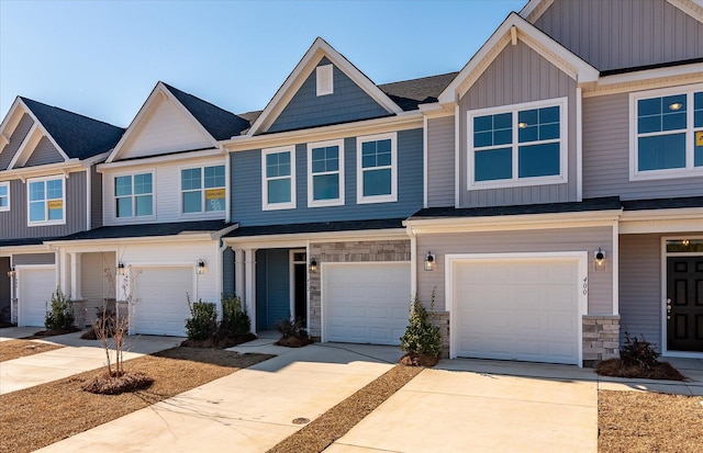 townhome / multi-family property with board and batten siding, concrete driveway, and stone siding