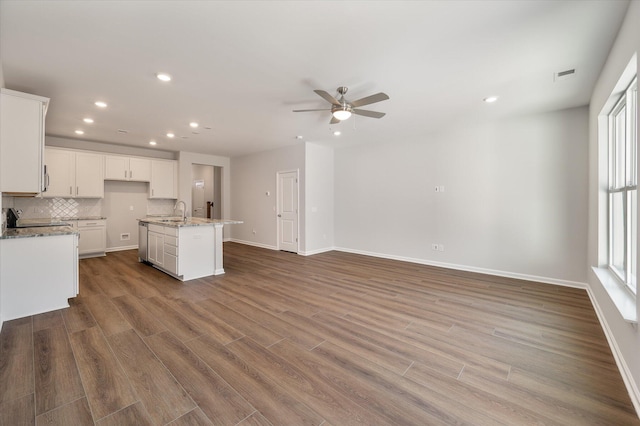 kitchen featuring wood finished floors, visible vents, a sink, stainless steel dishwasher, and backsplash