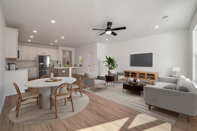 living room with light wood finished floors, visible vents, recessed lighting, and a ceiling fan