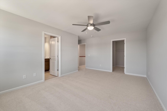 unfurnished bedroom with a closet, baseboards, light carpet, and a spacious closet