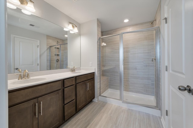 bathroom with double vanity, visible vents, a shower stall, and a sink