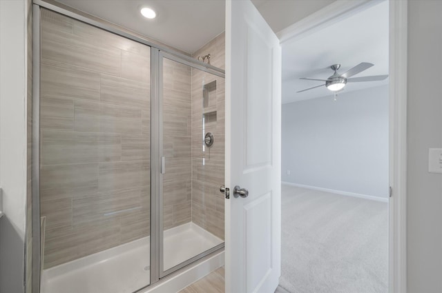 bathroom with baseboards, a ceiling fan, and a shower stall