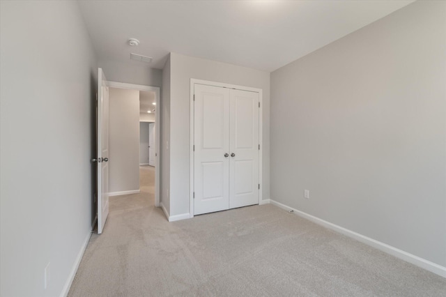 unfurnished bedroom featuring a closet, light colored carpet, and baseboards