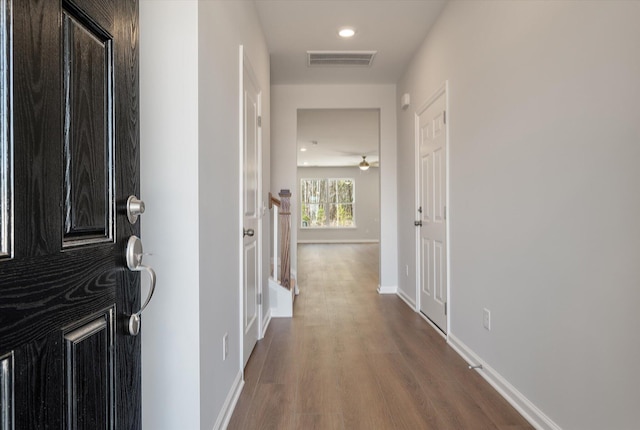 hallway featuring visible vents, recessed lighting, baseboards, and wood finished floors