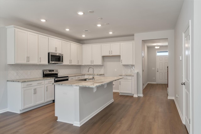 kitchen featuring light stone countertops, dark wood-style floors, white cabinets, stainless steel appliances, and a sink