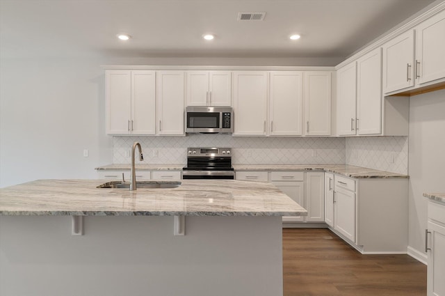 kitchen with visible vents, a sink, stainless steel appliances, dark wood-type flooring, and white cabinets