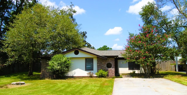 view of front facade with fence, a front lawn, brick siding, and stucco siding