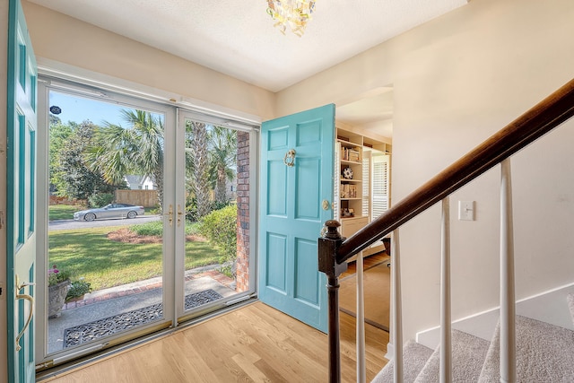 entryway with stairway, wood finished floors, and a chandelier