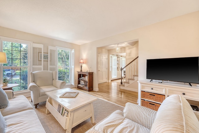 living area with baseboards, light wood finished floors, and stairs