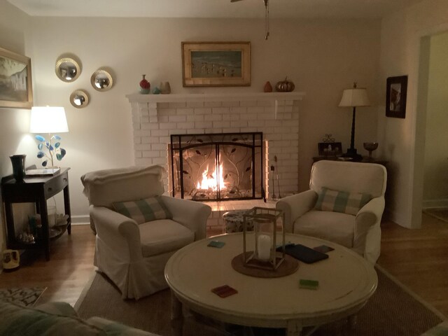 living room featuring wood finished floors, a brick fireplace, and baseboards