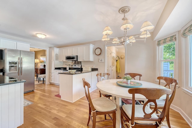 dining room featuring light wood-type flooring, baseboards, and a chandelier