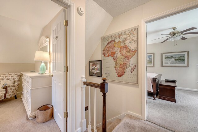 hall with light colored carpet, an upstairs landing, and baseboards
