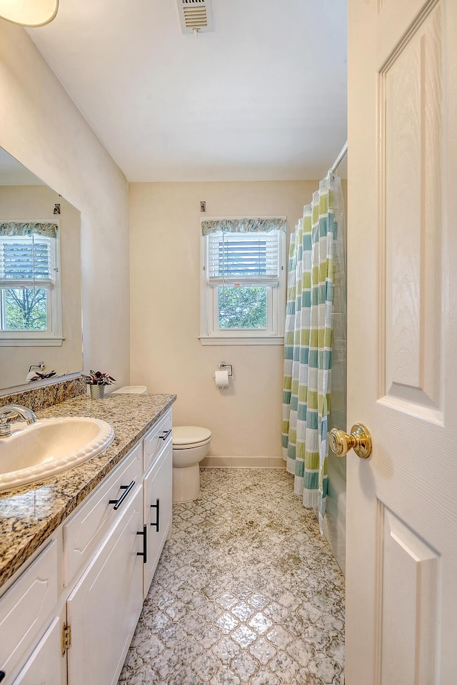bathroom featuring healthy amount of natural light, toilet, vanity, and baseboards