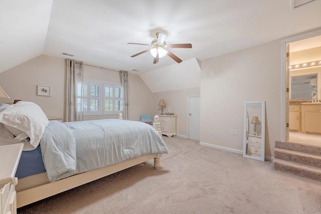 bedroom with lofted ceiling, ceiling fan, light colored carpet, baseboards, and connected bathroom