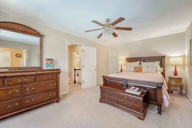 bedroom with light colored carpet, baseboards, a ceiling fan, and ensuite bathroom