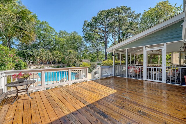 deck with a fenced backyard, a sunroom, and view of wooded area