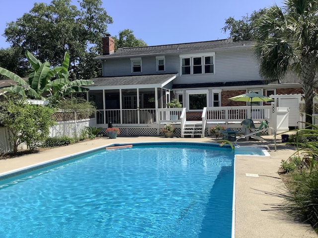 view of swimming pool with a sunroom, a wooden deck, and fence