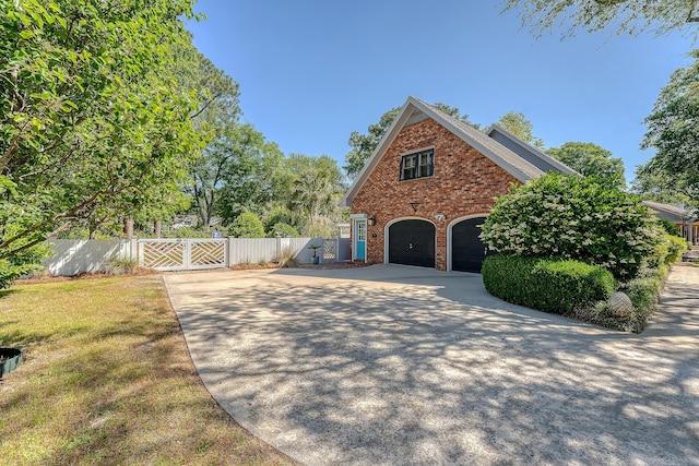 view of home's exterior featuring concrete driveway, fence, a gate, brick siding, and a garage
