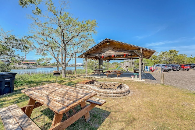 surrounding community with a fire pit, a water view, a lawn, and a gazebo