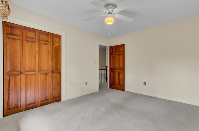 unfurnished bedroom featuring light colored carpet, a closet, and ceiling fan